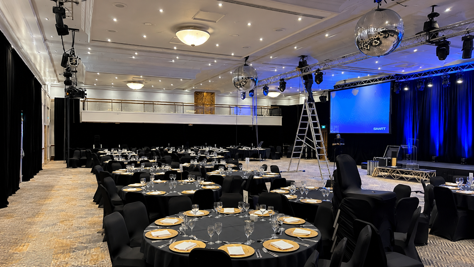 A ballroom dressed with black starcloth, mirror balls & blue stage lighting